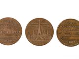 three bronze coins with the eiffel tower on them