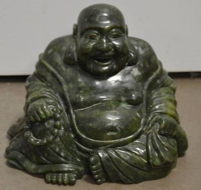une statue représentant un Bouddha souriant assis par terre