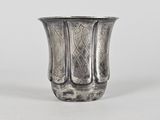 un vase ancien en argent posé sur une table blanche
