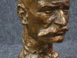 bronze bust of a man on a marble base with a black background