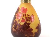 un vase jaune orné de fleurs rouges, posé sur un fond blanc