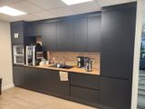 une photo d'une cuisine avec des placards noirs et des plans de travail en bois
