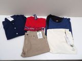 trois paires de pantalons pour homme et un polo posés sur une table