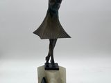 statue of a woman in a dress and hat on a marble base