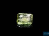 a green diamond on a black surface with a black background