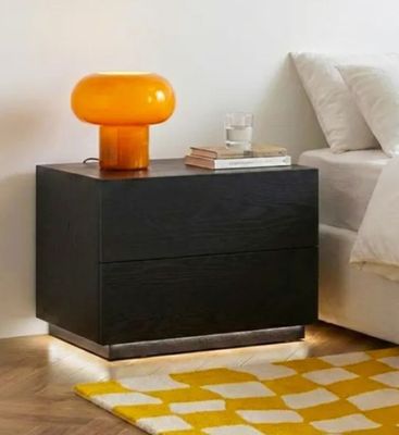 a black night stand with a yellow lamp on top of it
