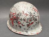 un casque blanc avec des traces de peinture rouge, posé sur une table