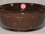 un bol marron avec un point rose dessus