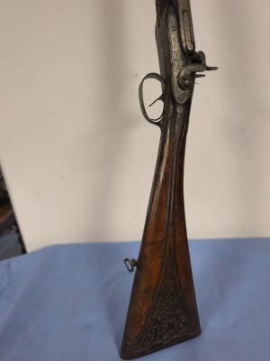 rifle on a blue tablecloth with a white wall in the background