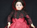 a doll that is wearing a red dress and a black hat