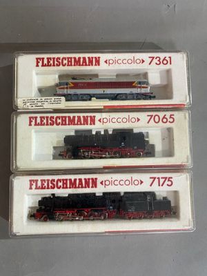 trois trains miniatures dans leurs boîtes, empilés les uns sur les autres