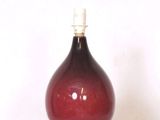 un vase rouge posé sur une étagère blanche, sur une surface blanche