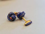 pair of blue and gold cufflinks with a red stone