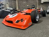 an orange race car that is parked in a garage