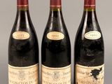 trois bouteilles de vin sont alignées sur une surface grise