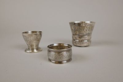 trois tasses en argent posées l'une à côté de l'autre sur une surface blanche