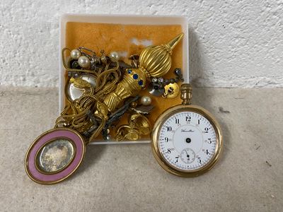 a gold clock and a pink and white pocket watch on the floor