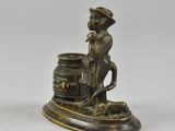 a bronze figurine of a man sitting on a barrel
