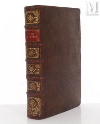 un vieux livre marron aux tranches dorées posé sur une table blanche