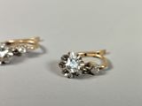 pair of gold and diamond earrings on a white surface