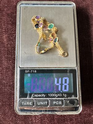 une balance numérique sur laquelle sont posés une horloge et un collier en or
