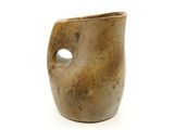 un vase marron troué posé sur une surface blanche