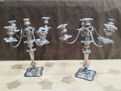 pair of silver candlesticks on a table with a brown background