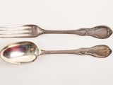 two spoons and a fork on a white surface