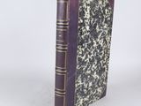 an old book sitting on top of a white table next to a white wall