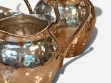 two silver pitchers sitting next to each other on a table