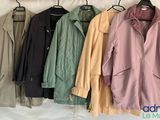 several jackets hanging on a rack in front of a white wall