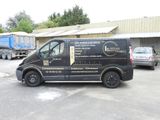 une camionnette noire garée sur un parking à côté d'un immeuble