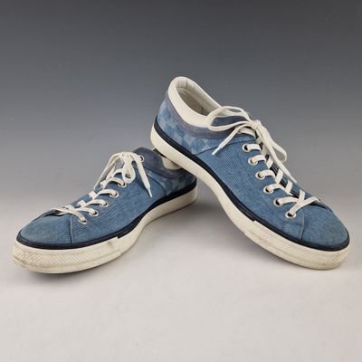 une paire de baskets bleues avec des lacets blancs, posée sur une surface blanche