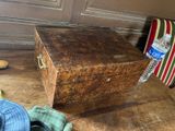 une boîte en bois posée sur un plancher en bois, à côté d'une paire de chaussures