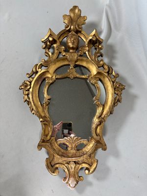 un miroir doré accroché au mur dans lequel on voit une femme