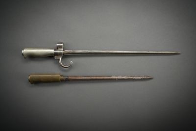two swords and a knife on a table with a gray background