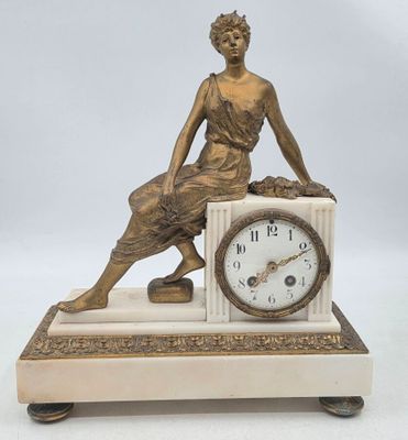 une statue de femme assise au sommet d'une horloge