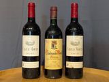 three bottles of wine are sitting on a wooden tray