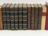 several old books are lined up in a row on a white surface