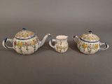two small teapots and a sugar bowl on a gray surface