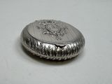 a silver box with a crest on it on a table