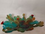 une sculpture en verre représentant un cactus posée sur une surface blanche