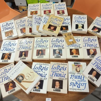 Plusieurs livres sont empilés sur une table devant une chaise.