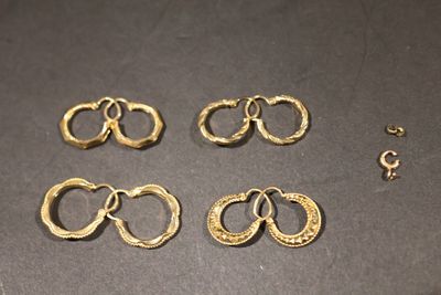 quatre paires de bagues en or et une paire de boucles d'oreilles posées sur une table