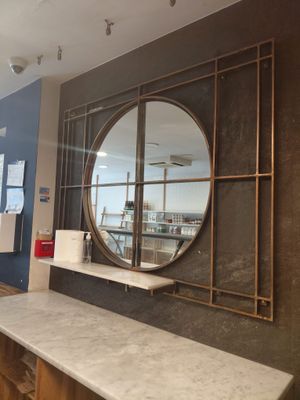 un grand miroir rond accroché au mur au-dessus d'un comptoir