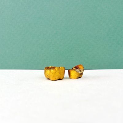 paire de boucles d'oreilles à clous plaquées or sur fond blanc avec un arrière-plan vert