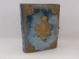 un petit livre bleu orné d'un motif doré