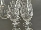 four wine glasses and a decanter on a table