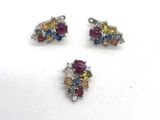 deux paires de boucles d'oreilles en pierre multicolores et un pendentif posés sur un fond blanc