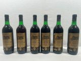 six bottles of wine are lined up on a white surface